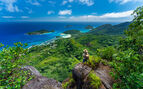 Woman standing on a rock over looking the sea and jungle after a hike