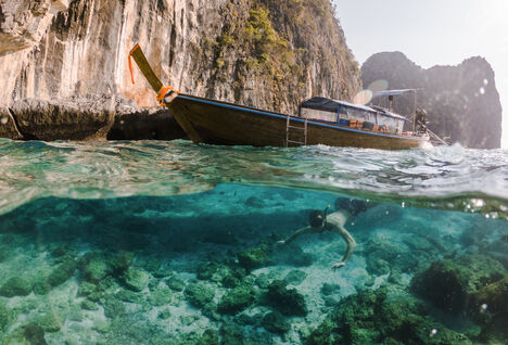 Water level photo showing a boat on the surface with a diver below in blue waters