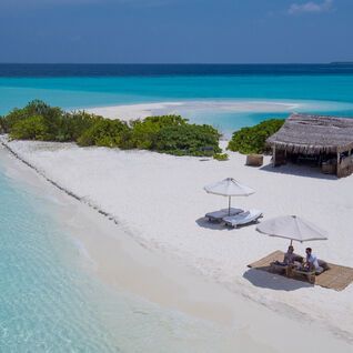 Picnic lunch on a white sand narrow beach in between blue waters in the Maldives
