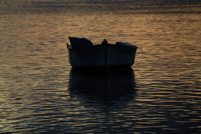 simple tender boat on the water at sunset with an orange sky 