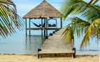 photo of a beach hut with someone laying in a hammock at overlooking the water