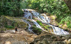 someone on a hike in the Belize national park with a water fall on one side