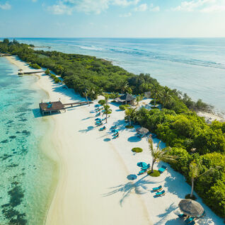 Aerial view of white sand beaches with a luxury resort and palm trees in the  Maldives