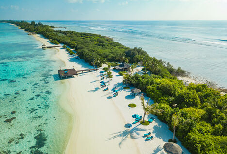 Aerial view of white sand beaches with a luxury resort and palm trees in the  Maldives