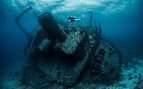 underwater photo of a scuba diver diving next to a wreckage of a large sunken ship in the Red Sea.