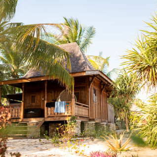 Wooden island beach cabin getaway, towels drying on the porch surrounded by palm trees