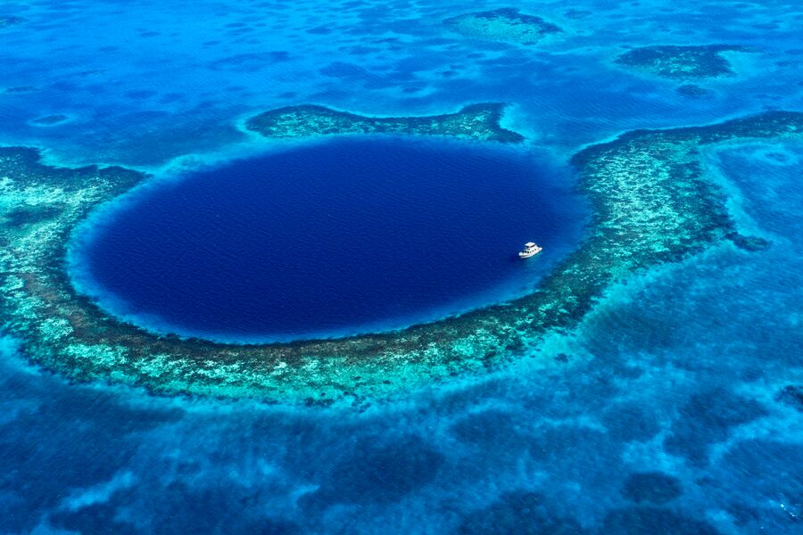 Aerial image of the blue hole in Belize with a diving boat in the middle of the blue hole
