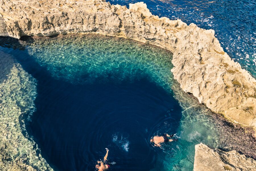 Aeirel photo of snorkellers exploring the Blue Hole with sand coloured stone around them