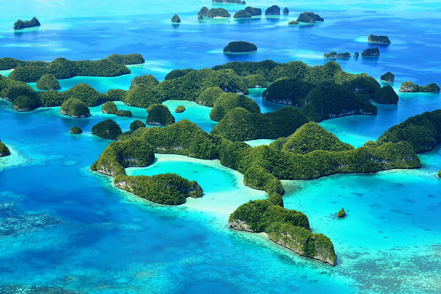Aeriel view of lush islets surrounding by sapphire blue waters with a clear blue sky