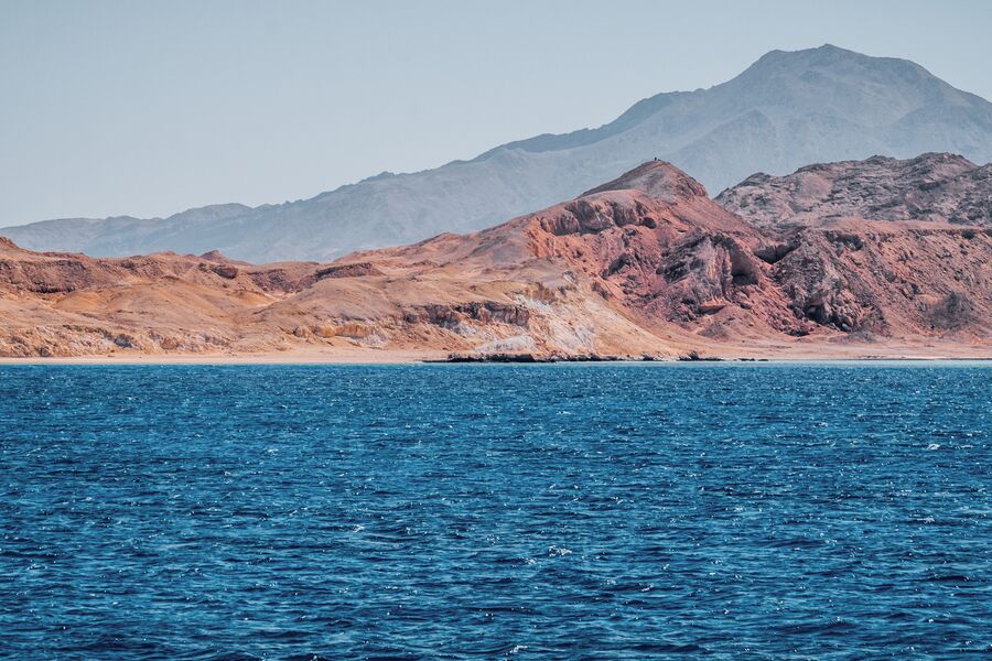 Water level shot of dark blue waters with a choppy surface and the rocky barren coast.