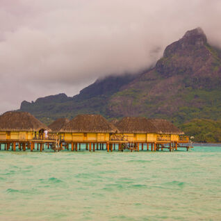 Huts on the water with sunset in the background in Tahiti