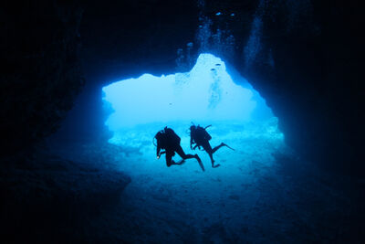 Scuba divers swimming through a cave.