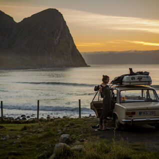 Man in a wetsuit standing by his car in Norway