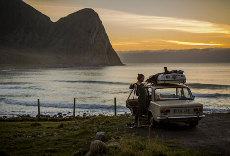 Man in a wetsuit standing by his car in Norway